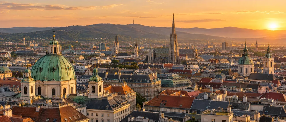 Blick über die Dächer von Wien mit Karlskirche und Stephansdom im Abendlicht